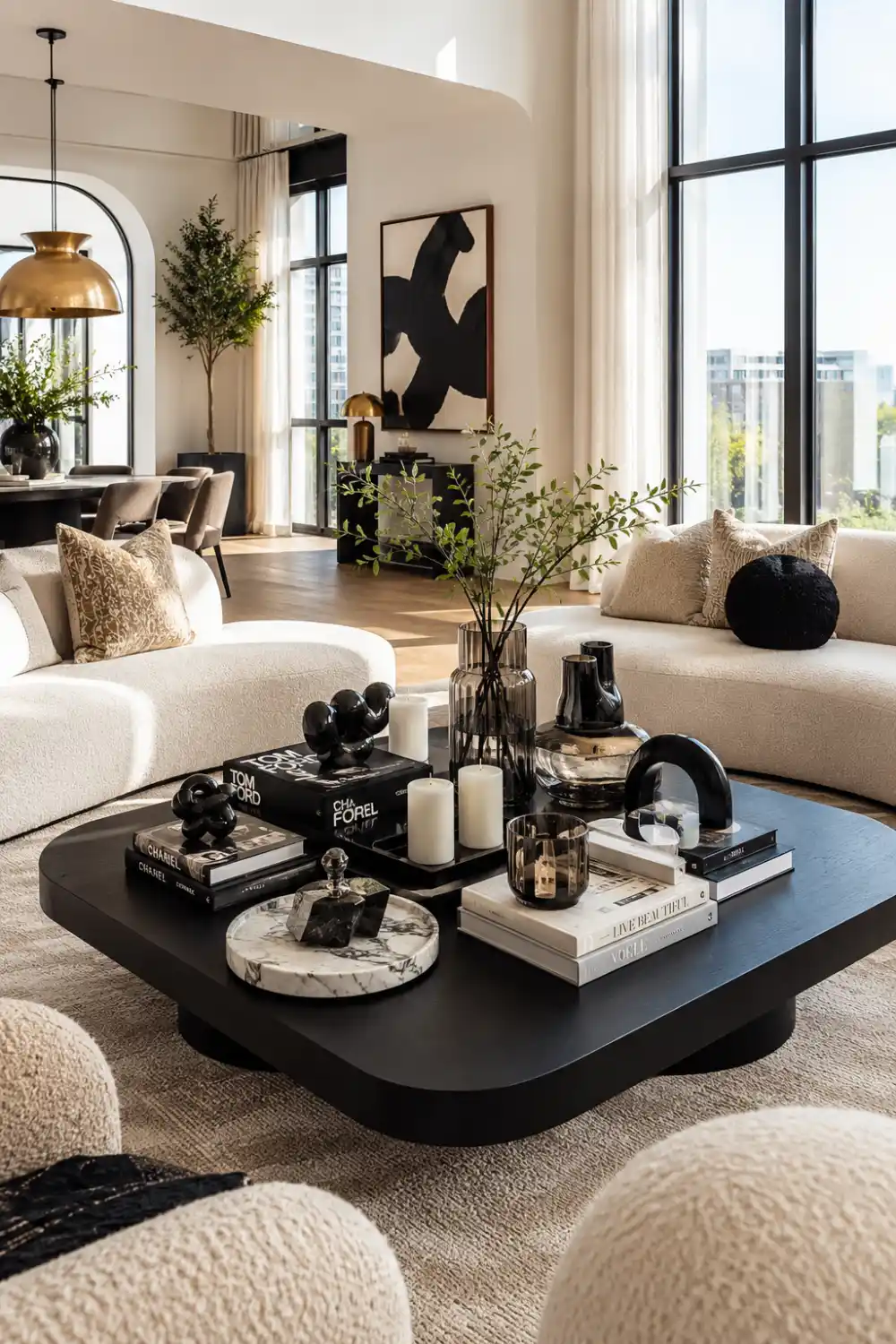 Modern luxury living room with a bold black coffee table styled using sculptural decor, designer books, candles, smoked 