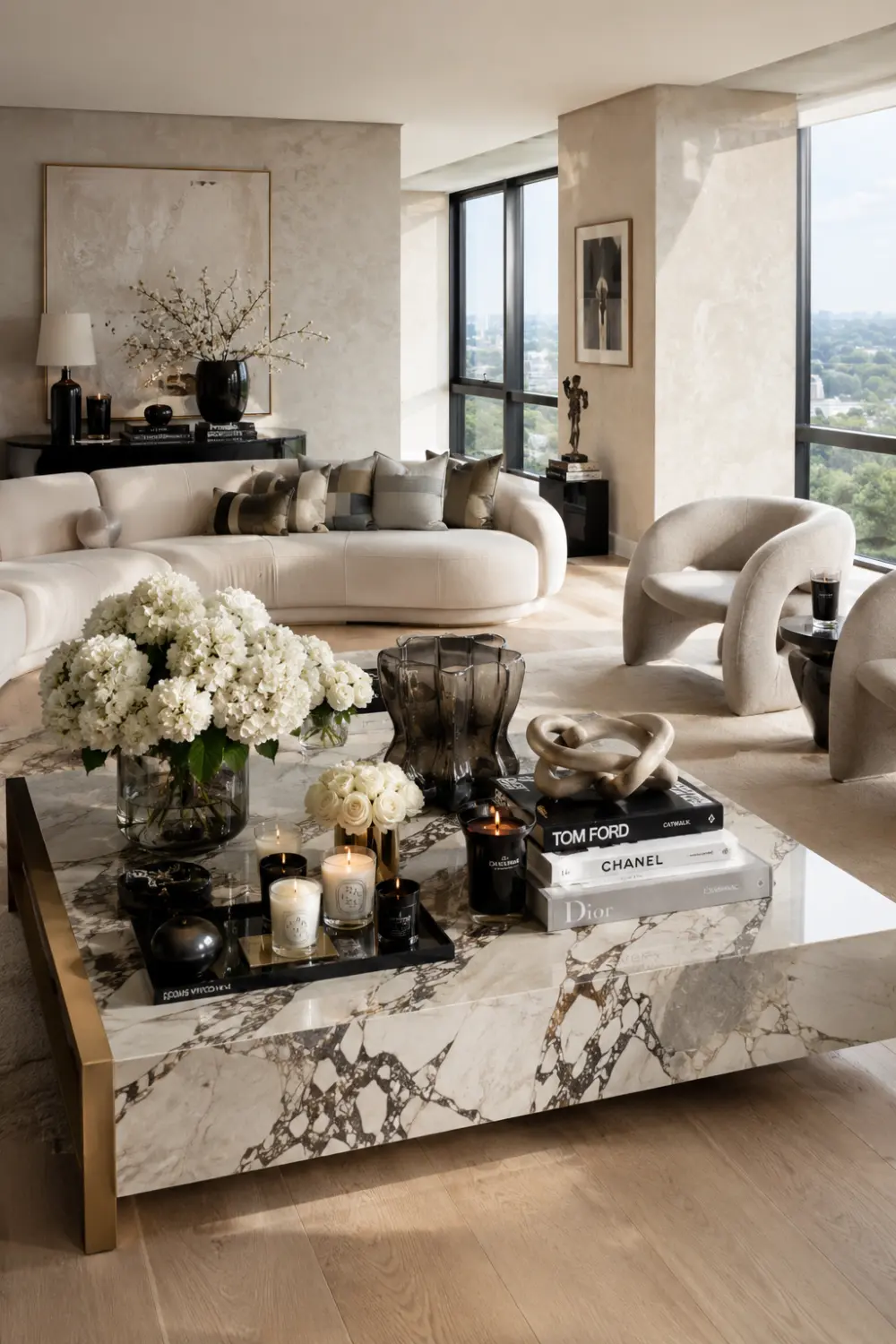 Modern glam living room with a large marble coffee table styled using black accents, designer books, candles, crystal de