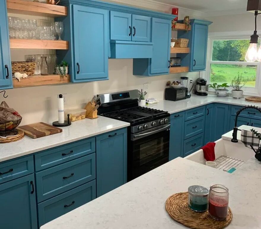 Blue kitchen cabinets with black handles and white countertops in a modern and stylish kitchen design.