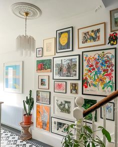 "An elegant gallery wall featuring a variety of framed artworks, each piece illuminated by sleek picture lights and