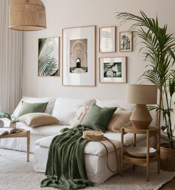 Cozy living room with green accents, white sofa, framed wall art, and lush indoor plants. Natural light and earthy tones
