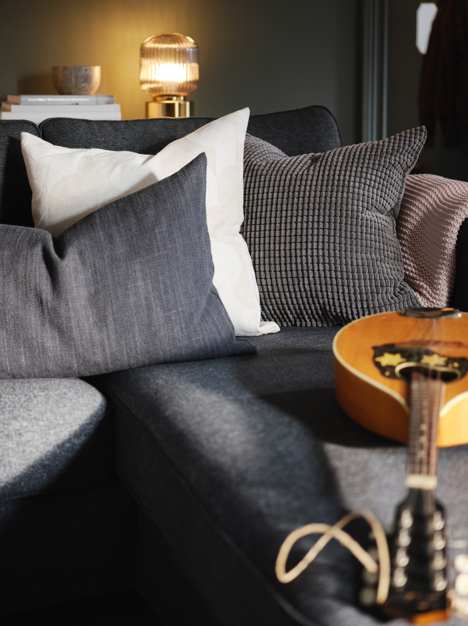 A cluster of textiles, including anthracite HILLARED and grey GULLKLOCKA cushions, and a string instrument on a PÄRUP so