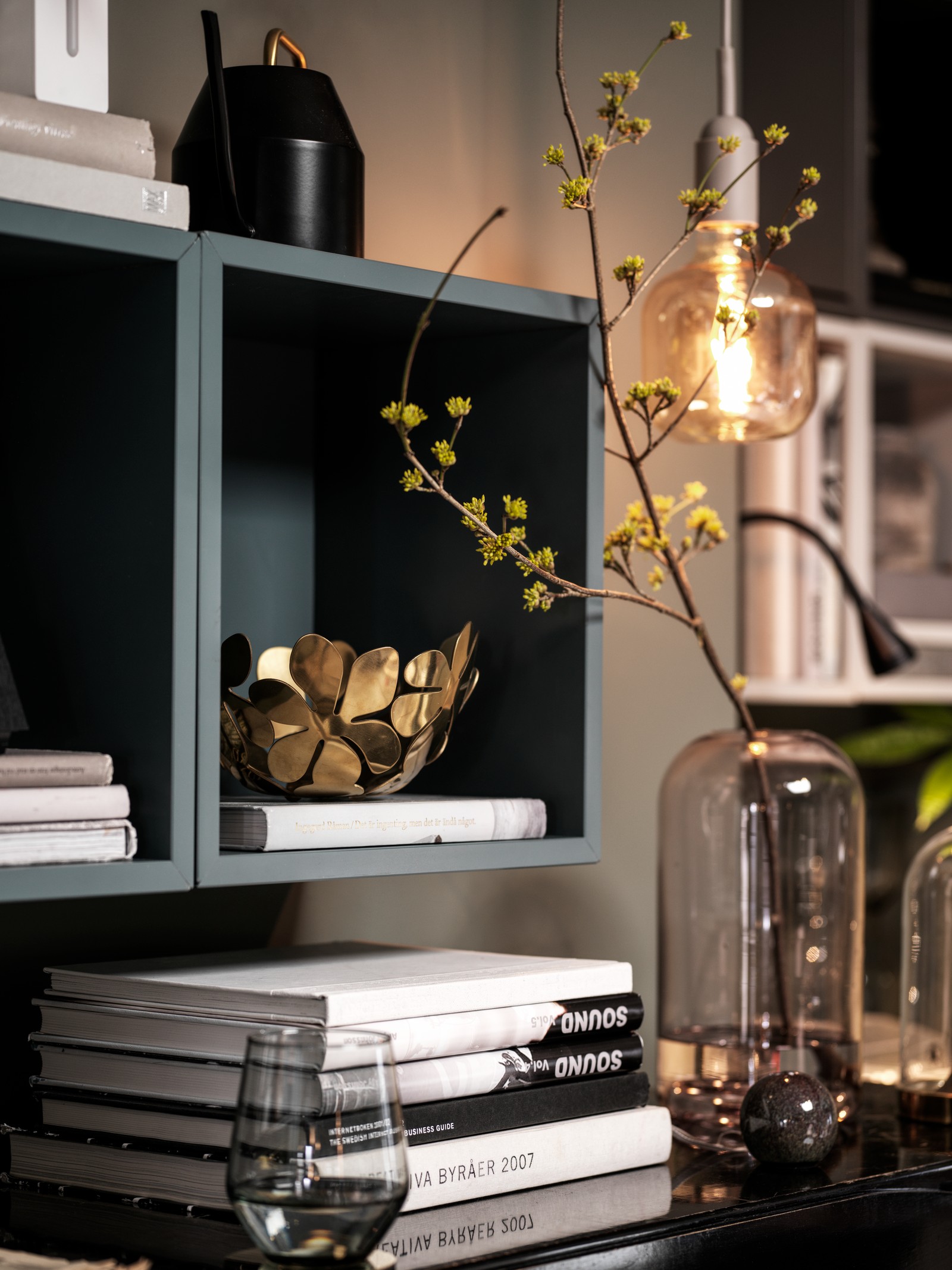 Grey-turquoise EKET wall-mounted shelving units on a living room wall, books and decorations in and around them.