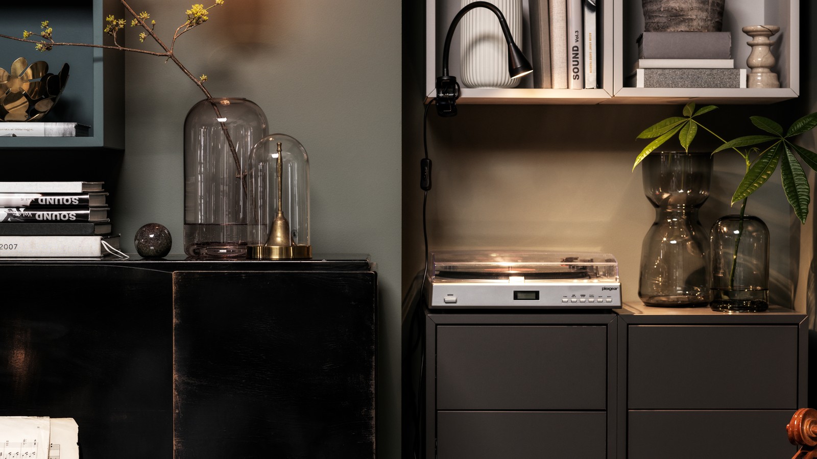 A piano next to a vertical arrangement of EKET cabinets. A record player, books and decorative glass dot free surfaces.