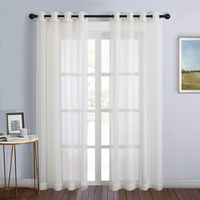 White room featuring sheer white curtains over a window providing a bright, airy dining room idea for family gatherings.
