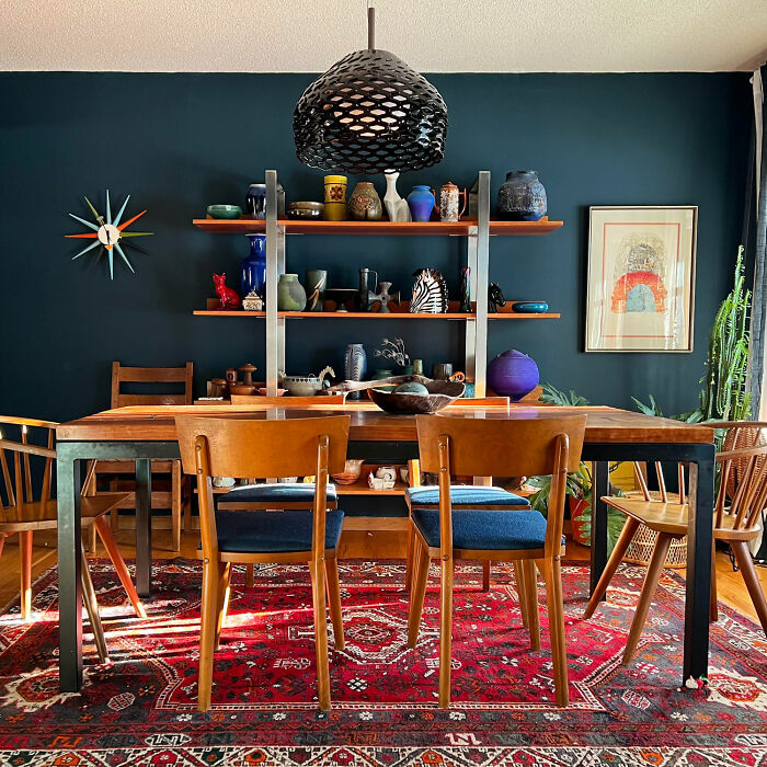 Dining room with dark blue walls, open shelves, wooden table and chairs, showcasing inspiring dining room ideas for fami