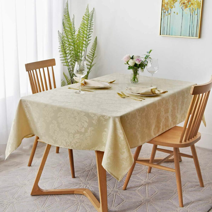 Dining room with wooden chairs, decorative tablecloth, flower centerpiece, and elegant table setting for family gatherin
