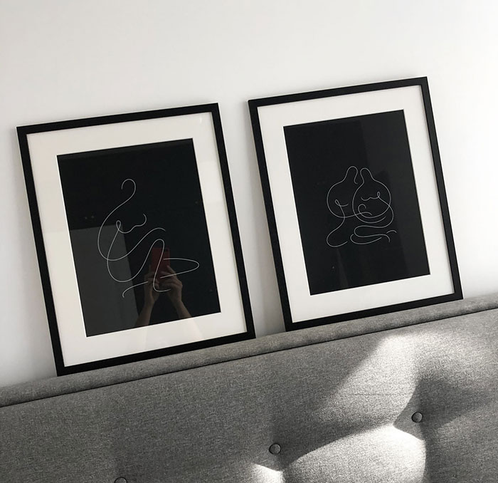 Two minimalist paintings with line art on a grey bedhead, showcasing modern home decor ideas and design style.