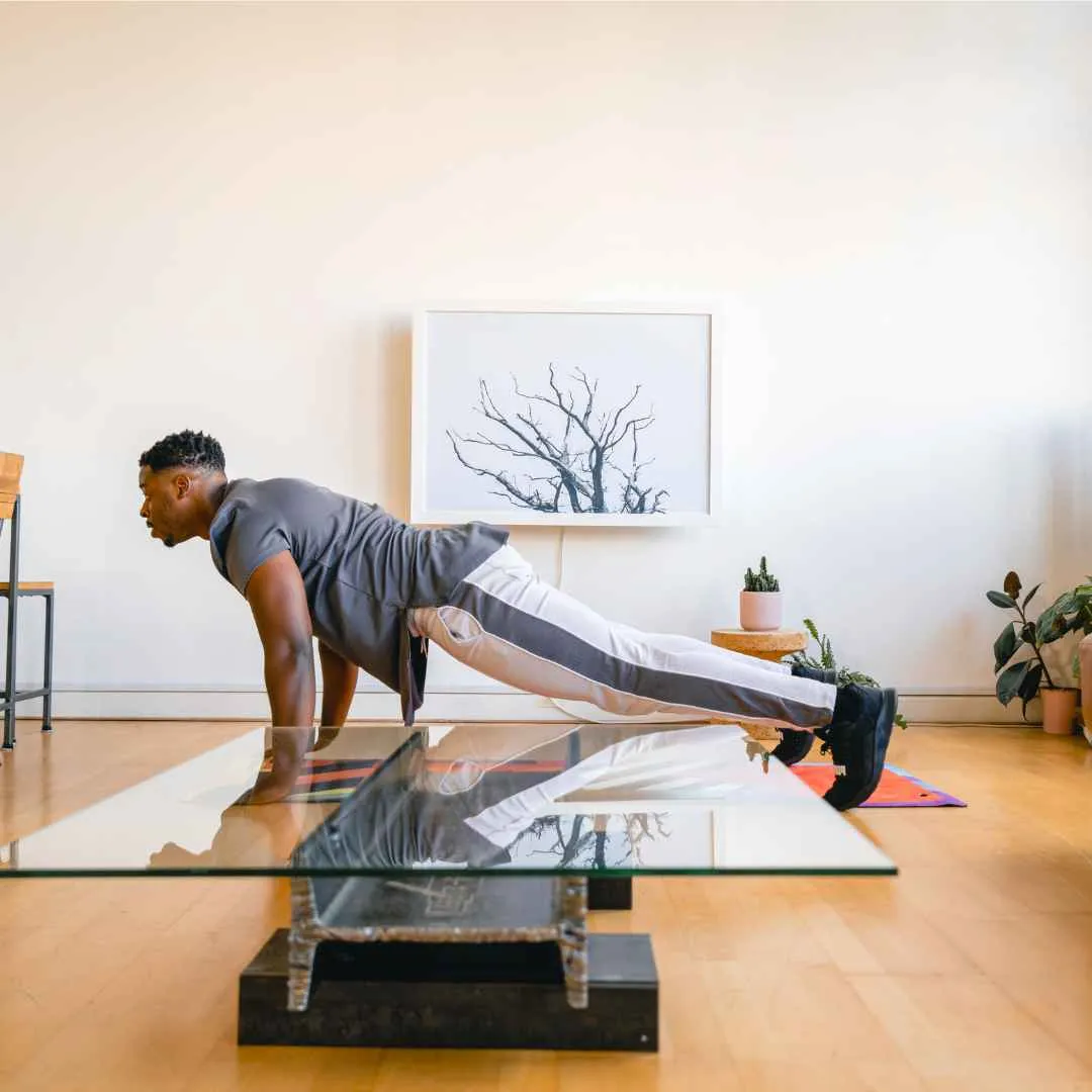 A fit man doing pushups on an exercise mat in front of his closed DropTop desk.