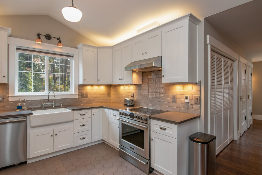 White kitchen cabinets with crown molding, stainless steel appliances, and modern lighting in a stylish kitchen renovati