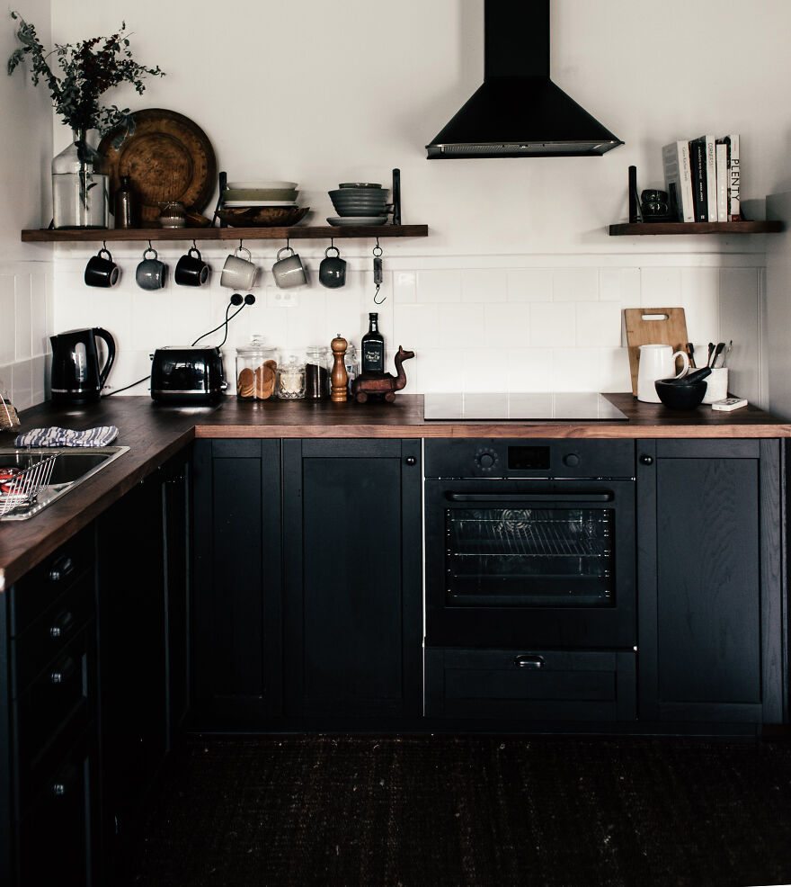 Black kitchen featuring modern and stylish kitchen cabinets with various appliances and wooden countertops.