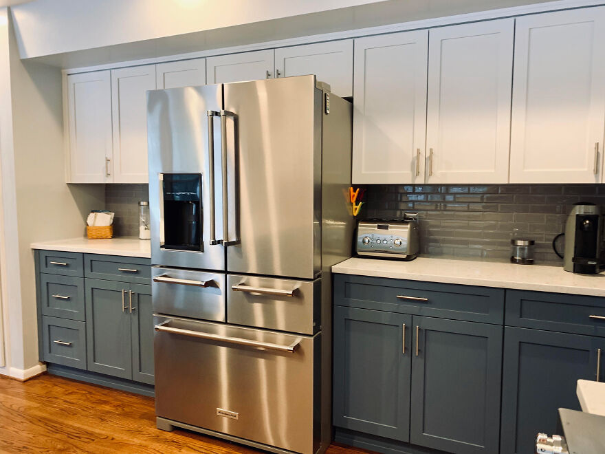 Big steel refrigerator in a modern kitchen featuring stylish white and grey kitchen cabinets with sleek hardware.