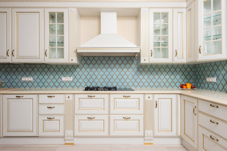Luxury kitchen cabinets with brass handles and decorative glass panels in a modern stylish kitchen design.