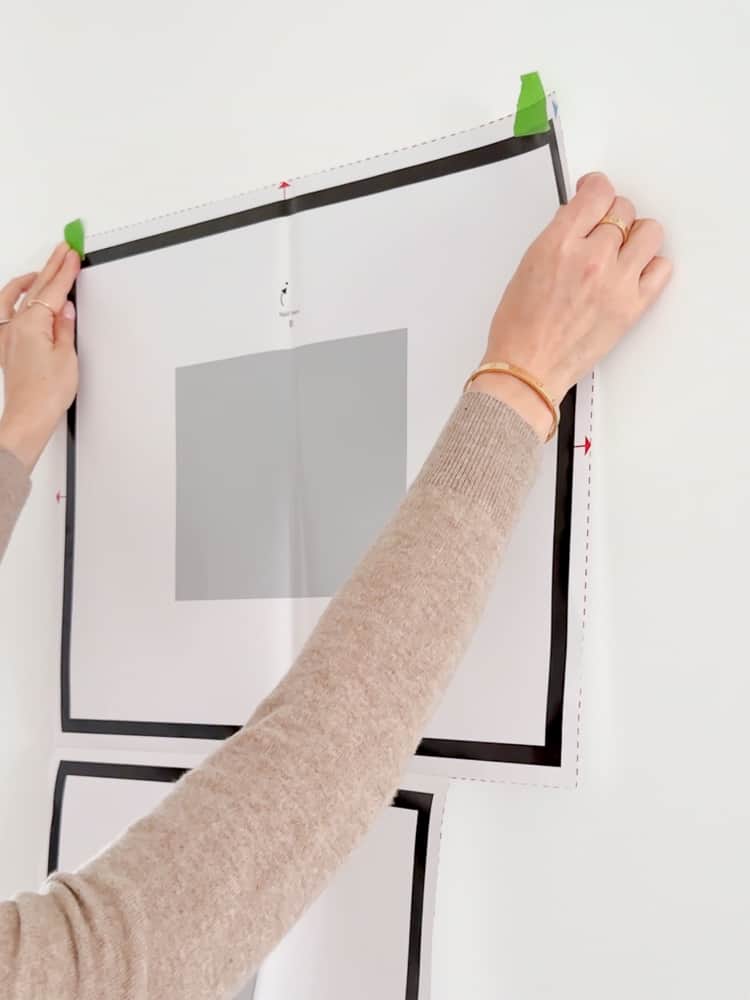 person taping template on the wall for picture frame