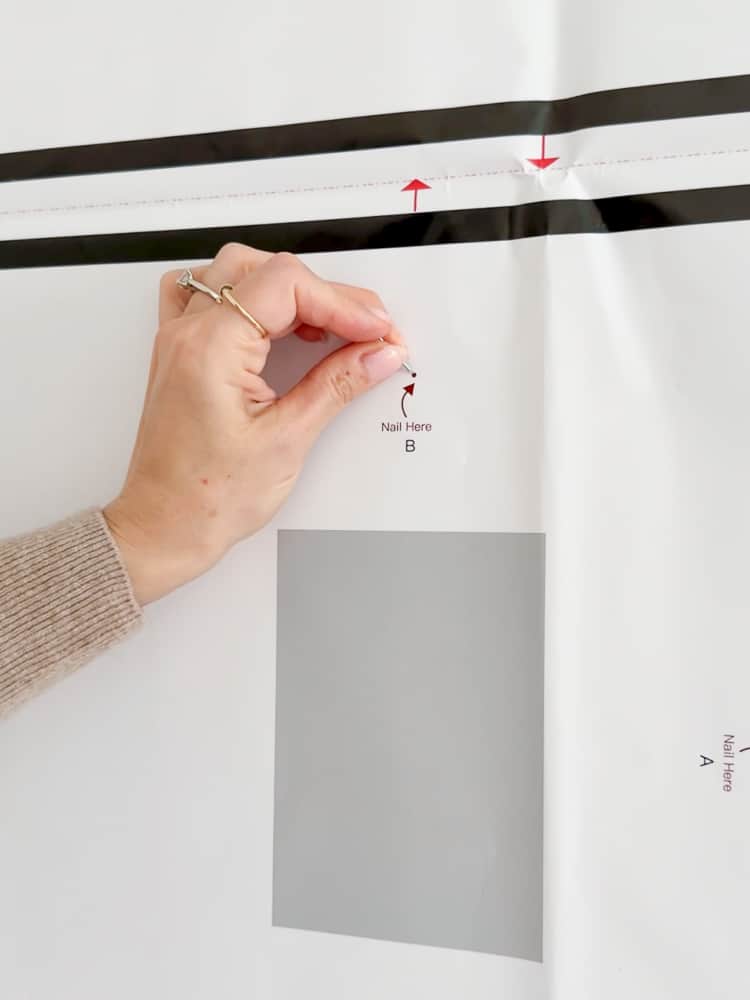 person demonstrating how to use a paper template to hang a picture frame