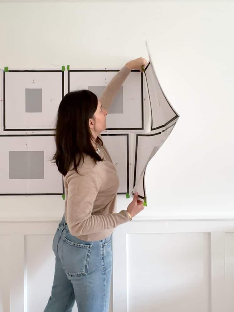 Stefana Silber pulling paper template off the wall after nails were hammered into the wall
