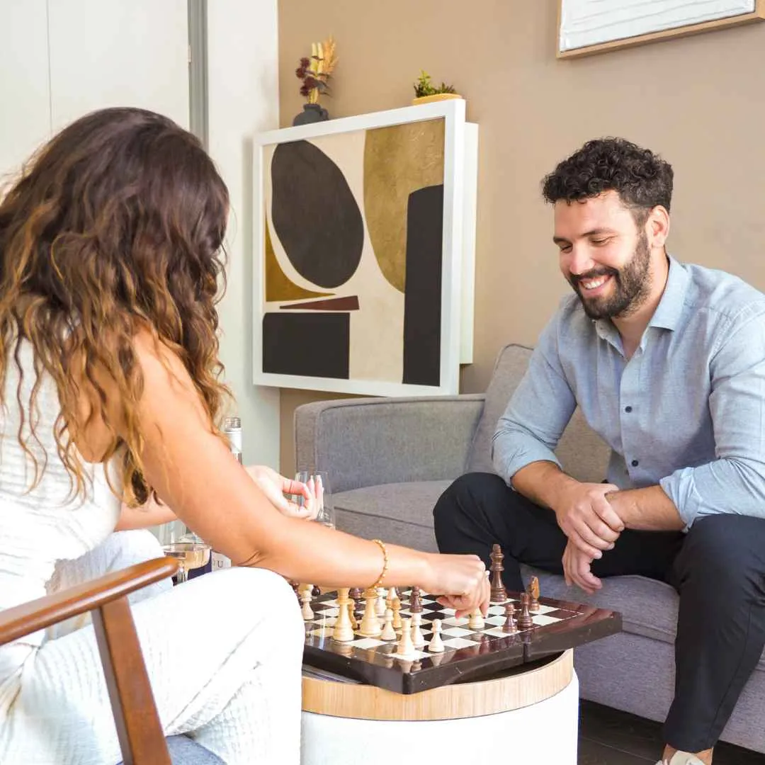 A couple playing chess on their coffee table with their Murphy desk in the background.