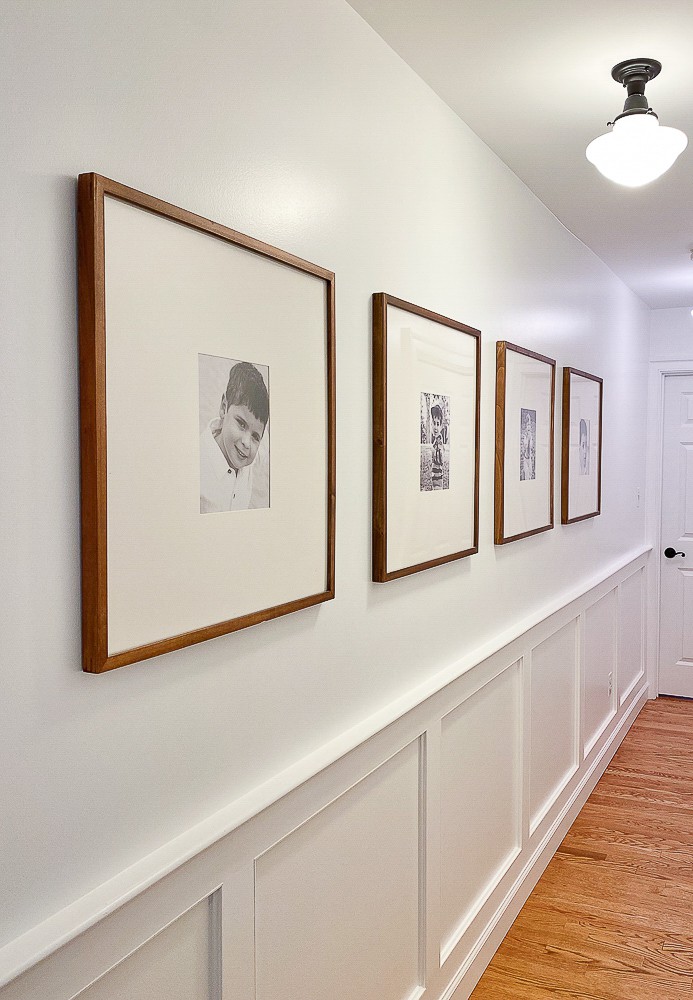 long hallway with black and white family photos in matching wood frames